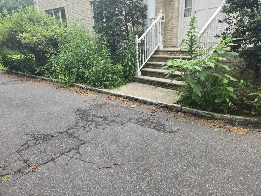 Driveway resurfacing in New Jersey — cracked, patched asphalt before resurfacing